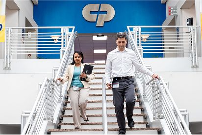 Empleados de Colgate-Palmolive bajando un tramo de escaleras con el logotipo de Colgate-Palmolive detrás de ellos sobre una pared azul.